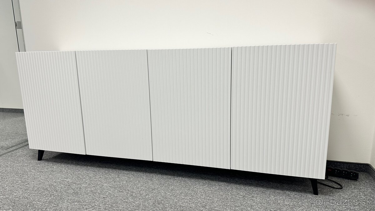 Biela komoda, dvierka maju zaujímavú štruktúru.