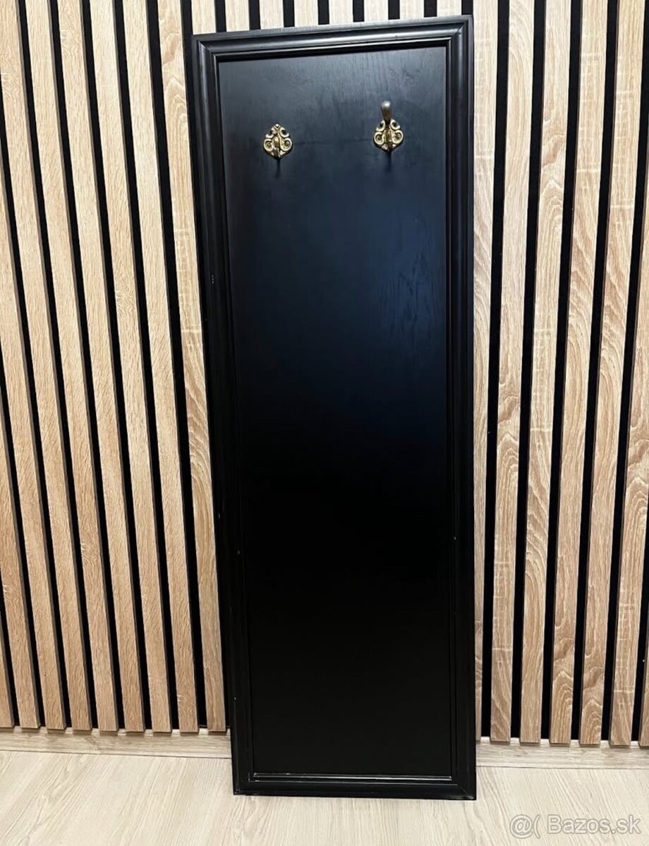 čierny drevený panel s vešiakmi