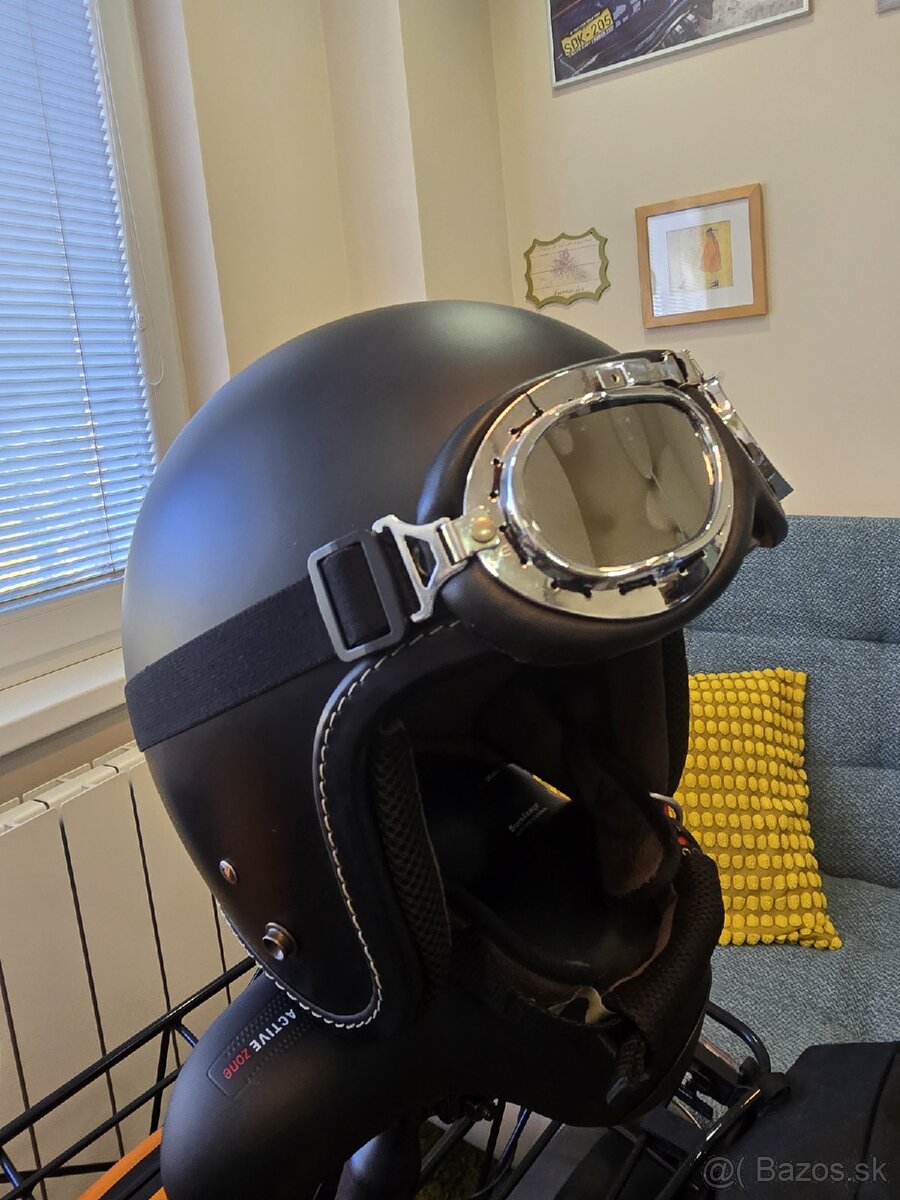 Otvorená motoprilba a okuliarmi.