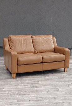 Pohovka dvojmiestna v koňakovom odtieni.