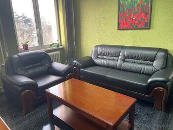 Čierna kožená sedacia súprava s dreveným obložením.