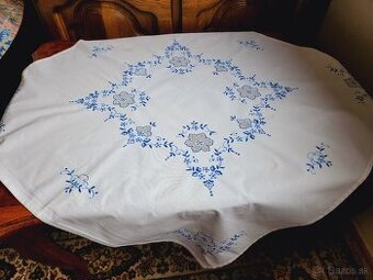 Krásny biely obrus zdobený bohatou modrou výšivkou kvietkov