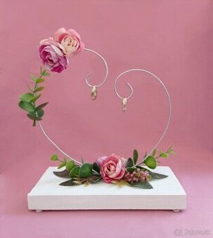 Svadobný stojan s ružovými kvetmi a zeleňou na obrúčky